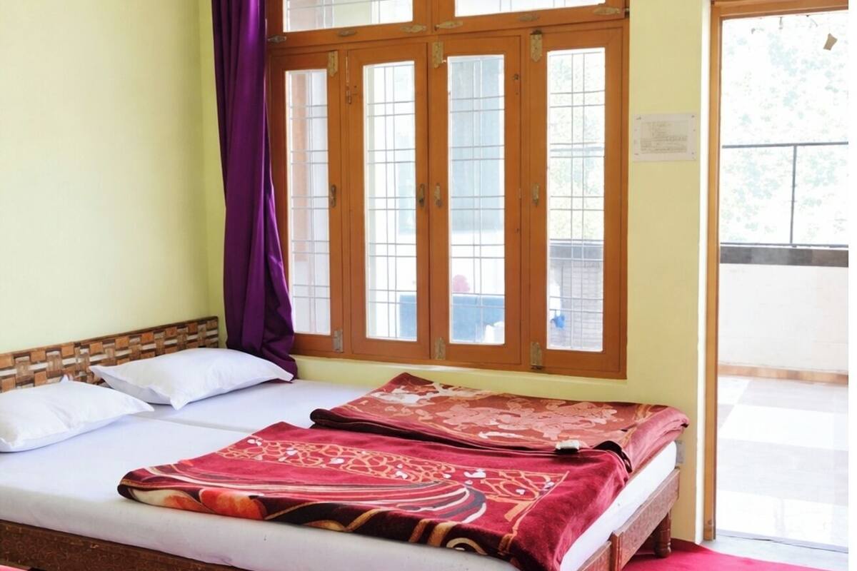 Une chambre avec deux lits, une fenêtre avec un rideau et une moquette rouge.