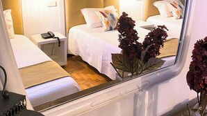 Une chambre avec deux lits, une table de chevet avec un téléphone, un luminaire suspendu et un vase avec des fleurs.