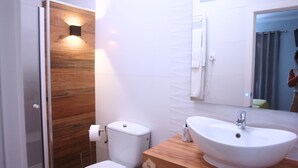 Une salle de bain avec un mur recouvert de panneaux en bois, des toilettes, un lavabo et un miroir.
