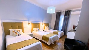 Une chambre d’hôtel avec deux lits, un bureau, une chaise et un lustre.