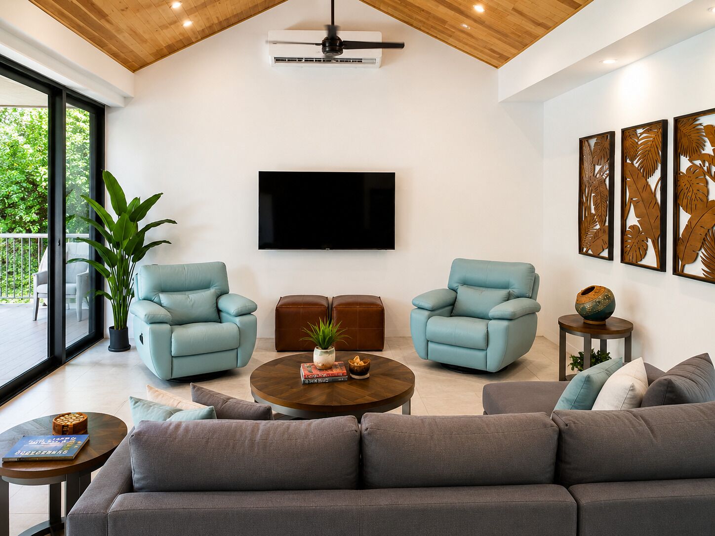 Una sala de estar moderna con una televisión de pantalla plana, dos sillones azul claro, un sofá gris, una mesa de centro de madera y una mesita auxiliar con un jarrón decorativo.