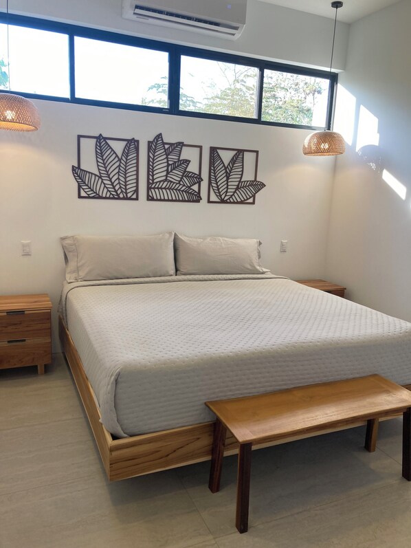 A bedroom with a bed, bedside tables, a bench, and wall art. - A Private Sanctuary in Playa Avellanas (Guanacaste Province)
