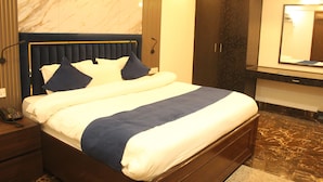Una habitación de hotel con cama, mesita de noche, teléfono, armario y espejo.