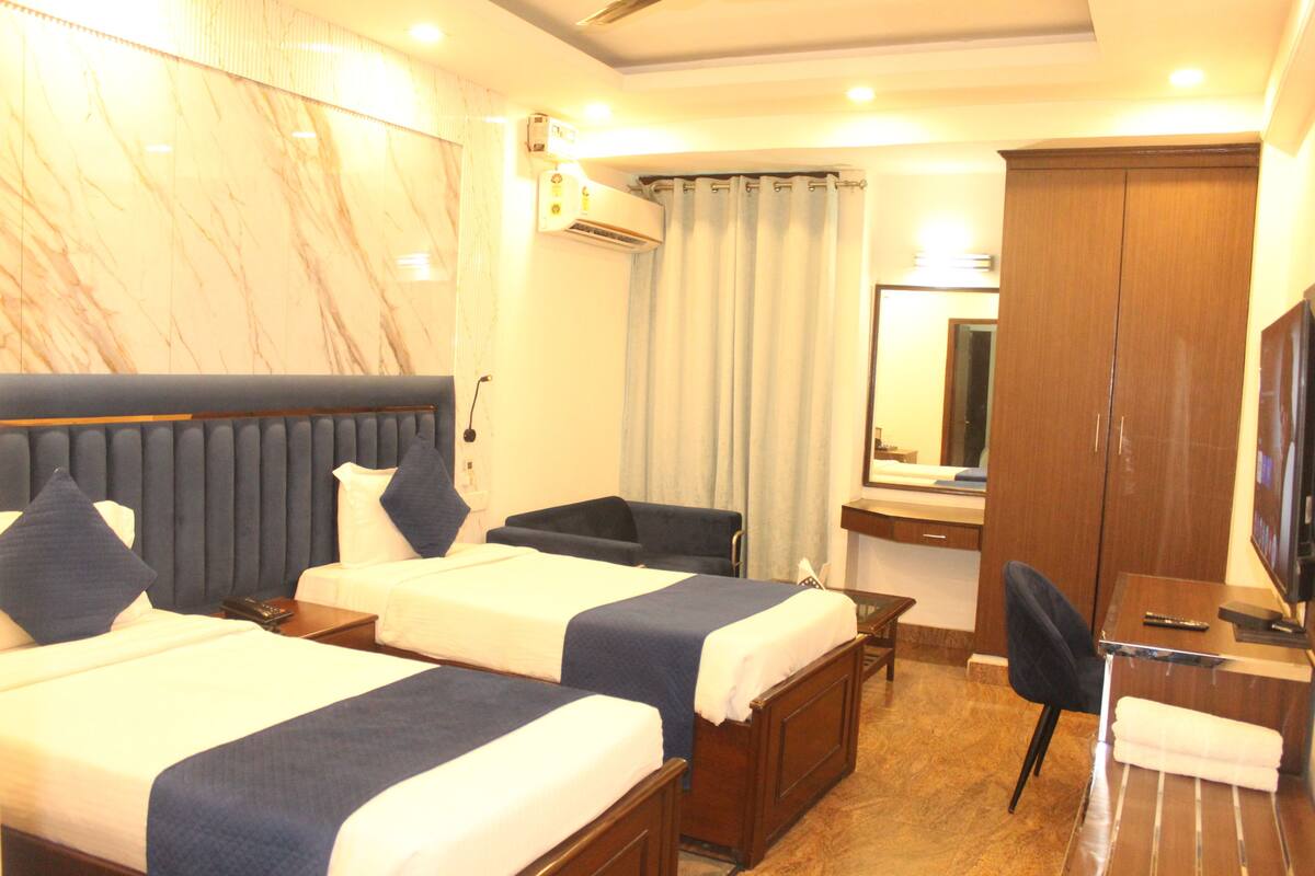 A hotel room with two beds, a desk, a chair, a TV, and a wardrobe.