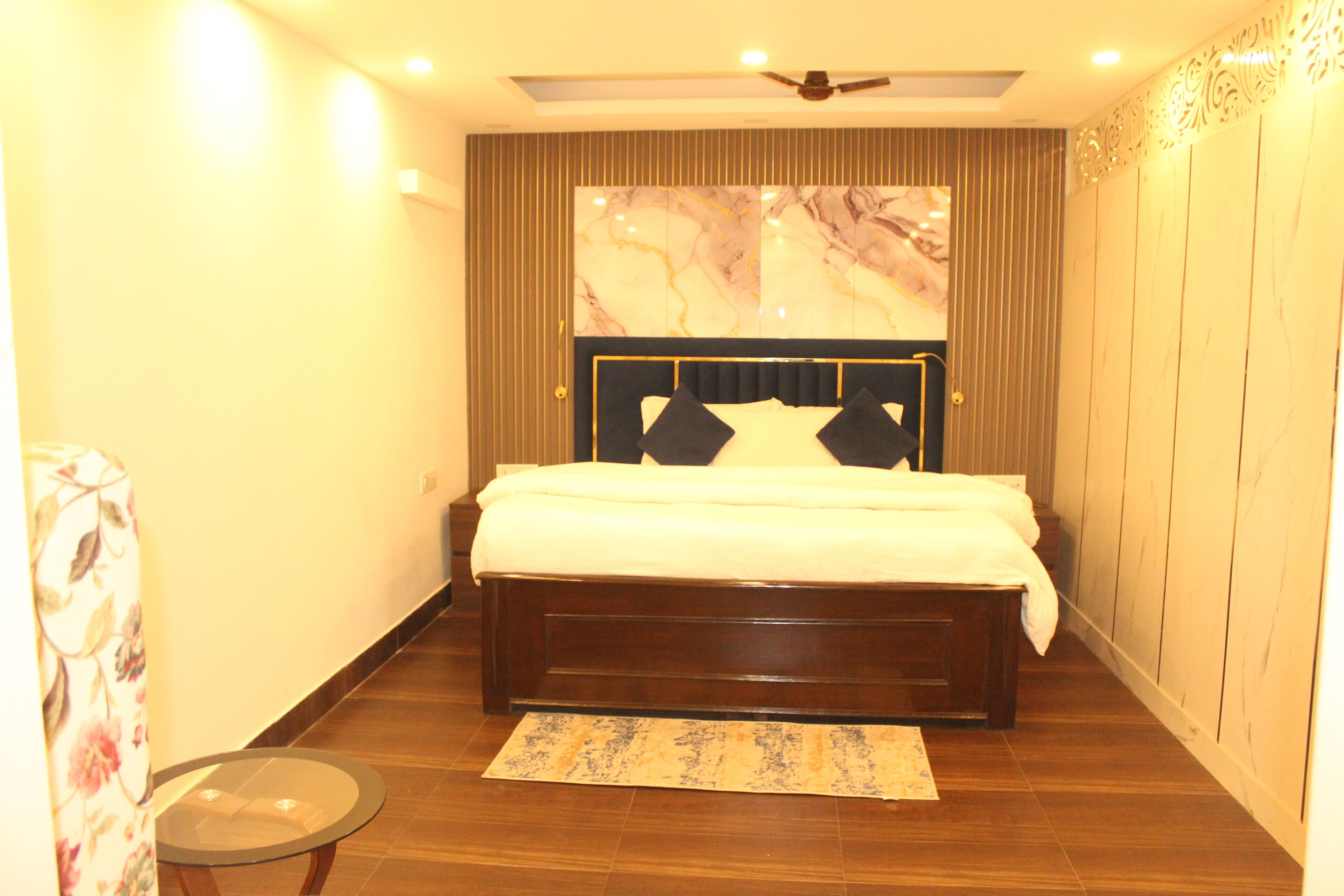 A bedroom with a bed, a ceiling fan, and a marble wall.
