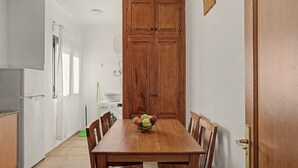 A compact kitchen with a wooden dining table, a washing machine, and a refrigerator.