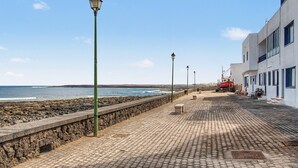 A coastal walkway with stone walls, benches, and street lamps.