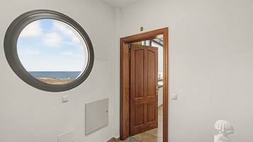 Een kamer met een rond raam, een houten deur en uitzicht op het strand.
