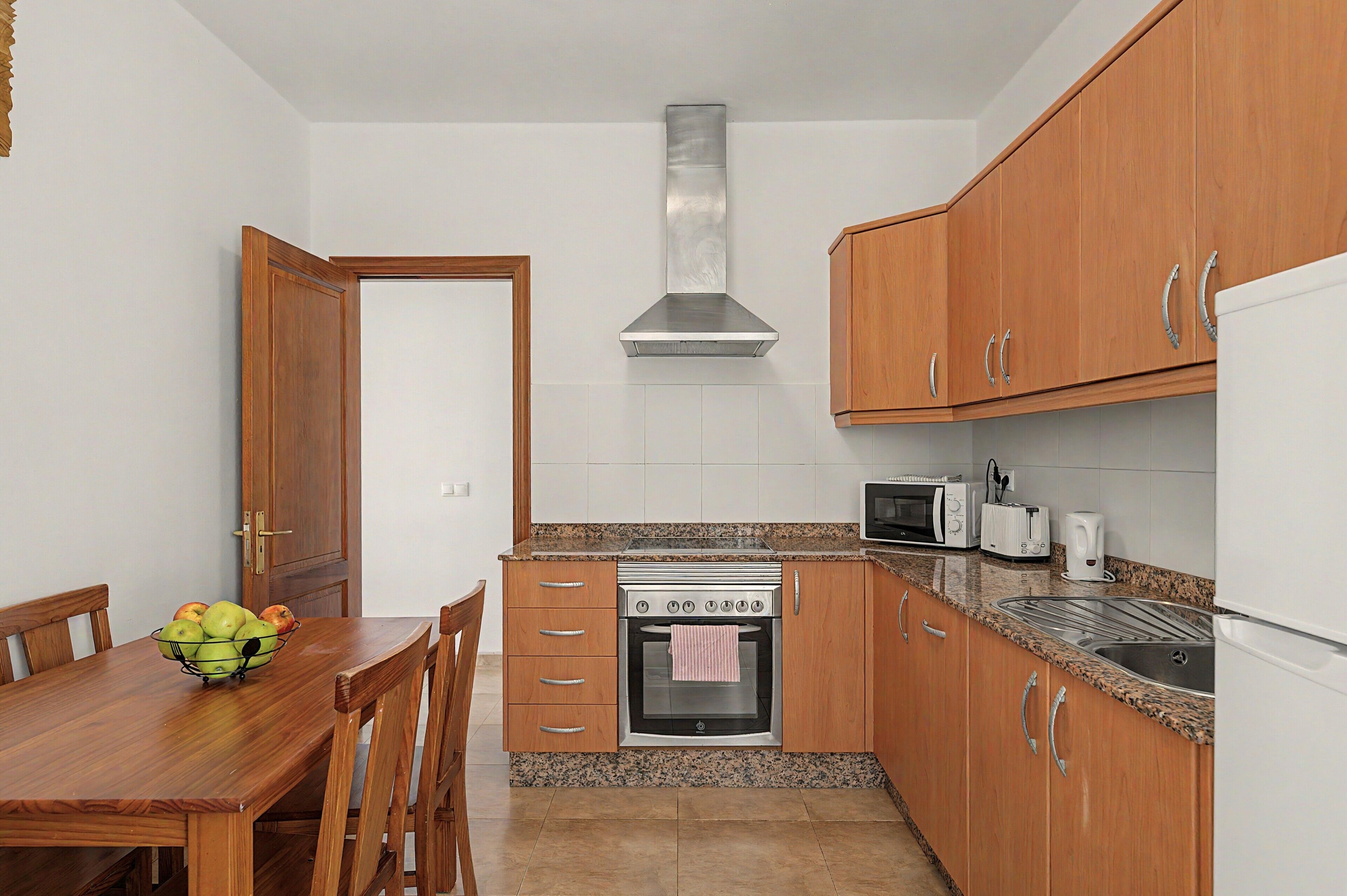 Una cocina compacta con armarios de madera, un horno de acero inoxidable, un microondas y un tostador.