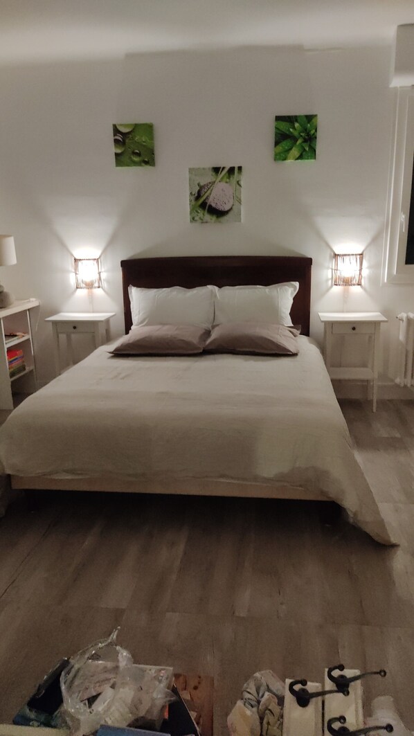 Une chambre à coucher comprenant un lit, deux tables de chevet, une commode, une lampe et des œuvres d’art murales.