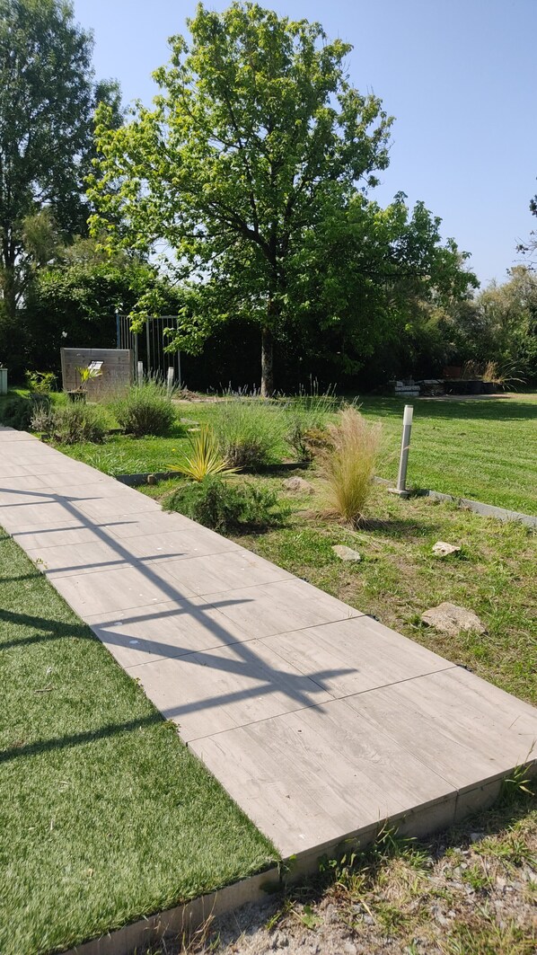 Un sendero atraviesa un área ajardinada con césped, plantas y árboles.
