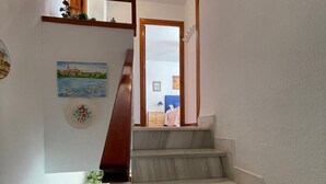A staircase with a wooden handrail, white walls, and artwork. - Terrasol Isis D Plex A 1 Minuto DE LA Playa (Velez-Malaga)