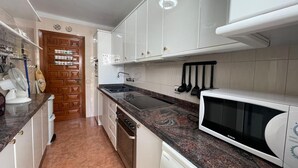 A kitchen with white cabinets, a granite countertop, a microwave, and a dishwasher. - Terrasol Isis D Plex A 1 Minuto DE LA Playa (Velez-Malaga)