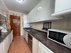 A kitchen with white cabinets, a granite countertop, a microwave, and a dishwasher. - Terrasol Isis D Plex A 1 Minuto DE LA Playa (Velez-Malaga)