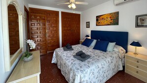 A bedroom with a bed, a ceiling fan, a painting, and a mirror. - Terrasol Isis D Plex A 1 Minuto DE LA Playa (Velez-Malaga)