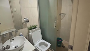 A bathroom with a sink, toilet, and glass shower enclosure. - Cozy 1-bedroom condo in perfect Manila with AC pool and fitness (Manila)