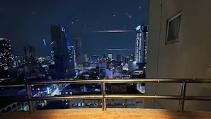 A nighttime cityscape view from a balcony with a railing. - Cozy 1-bedroom condo in perfect Manila with AC pool and fitness (Manila)