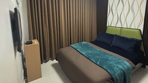 A hotel room with a bed, curtains, a wall-mounted air conditioner, a ceiling light, and a patterned wall. - Cozy 1-bedroom condo in perfect Manila with AC pool and fitness (Manila)