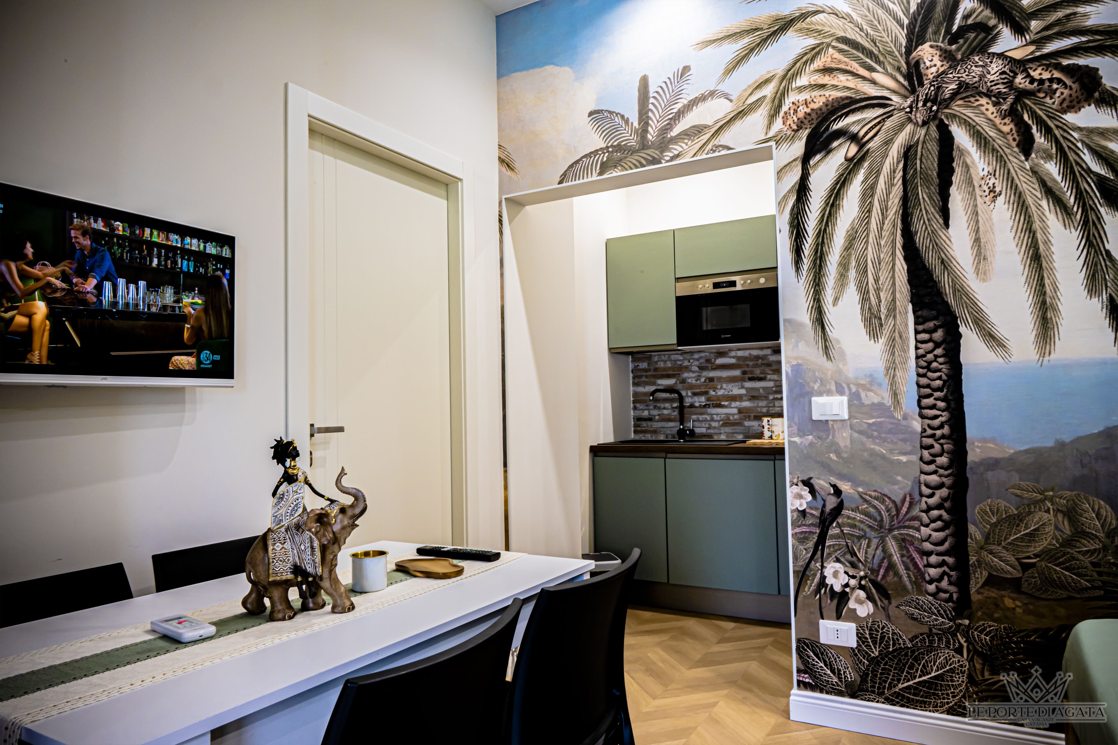 A dining area with a long table, chairs, a television, and a decorative elephant figurine.