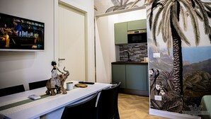 Un espace repas comprenant une longue table, des chaises, un téléviseur et une statuette d’éléphant décorative.