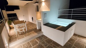 Een moderne keuken met een vast eiland, witte keukenkastjes en een eethoek met een tafel en stoelen.