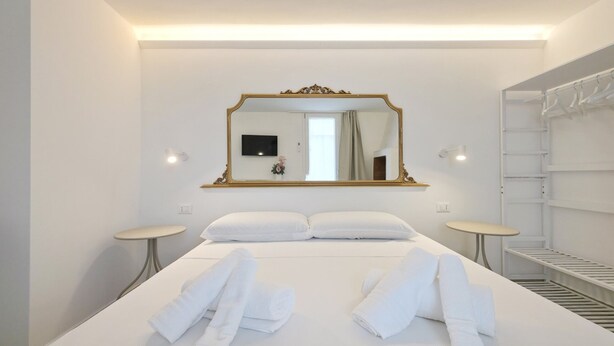 Een hotelkamer met een groot bed, twee nachtkastjes, een aan de muur bevestigde televisie, een spiegel en een inbouwkast.