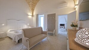 Een slaapkamer met een bed, een bank, een kleine tafel, een spiegel en een open haard.