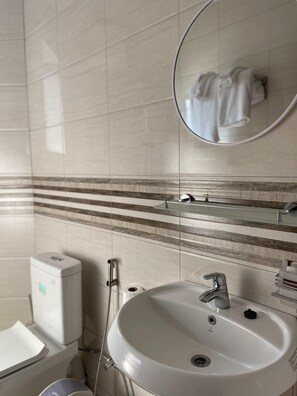 A bathroom with a white sink, a mirror, and a towel rack.
