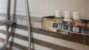 Un baño con ducha, un perchero y un estante con tres artículos de aseo.