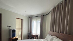 Una habitación de hotel con una cama grande, un escritorio, una silla y un televisor.