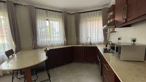 Una cocina moderna con una isla curva, armarios empotrados y un ventanal con cortinas.