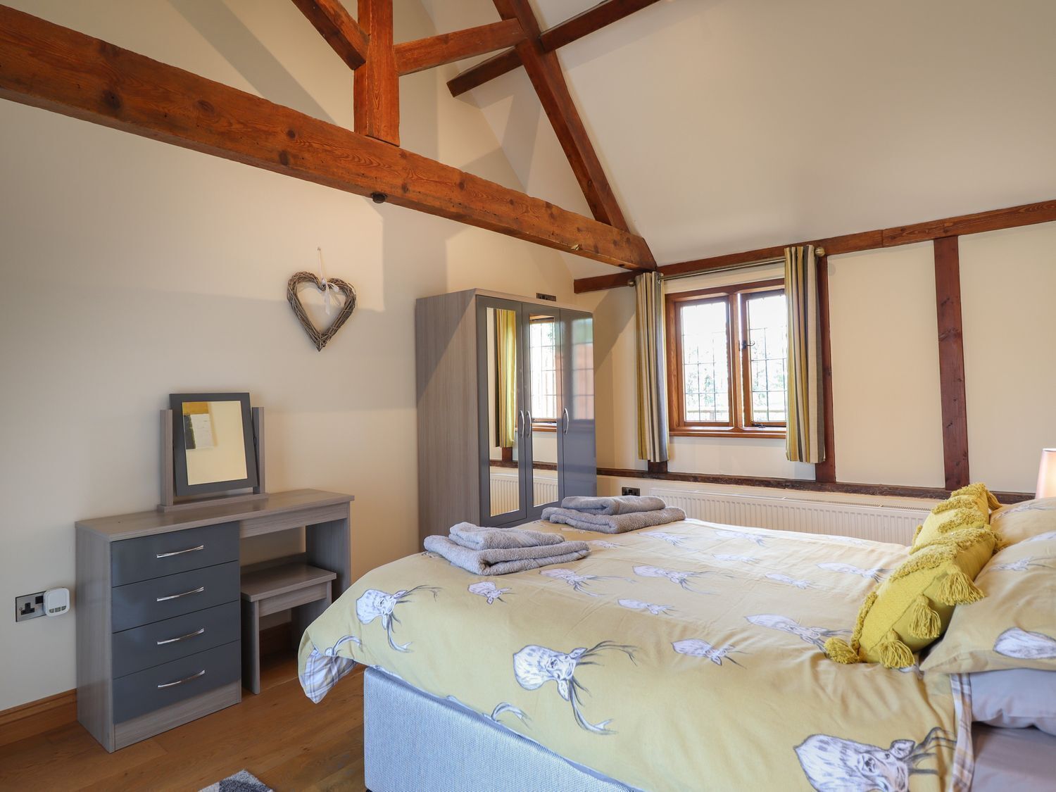 A bedroom with a bed, a wardrobe, a desk, a mirror, and a window.