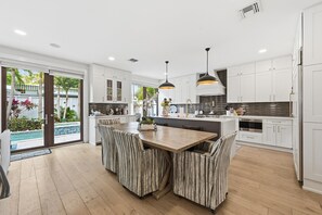 A modern kitchen with white cabinetry, a central island, and striped chairs. - Mermaids Cove - Luxury Meets Location - 5BD/5.5Bath, May - August 10% off (Key West)