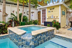 A swimming pool with a tiled edge, surrounded by plants and a building with a sign reading 'TIKI BAR'. - Mermaids Cove - Luxury Meets Location - 5BD/5.5Bath, May - August 10% off (Key West)