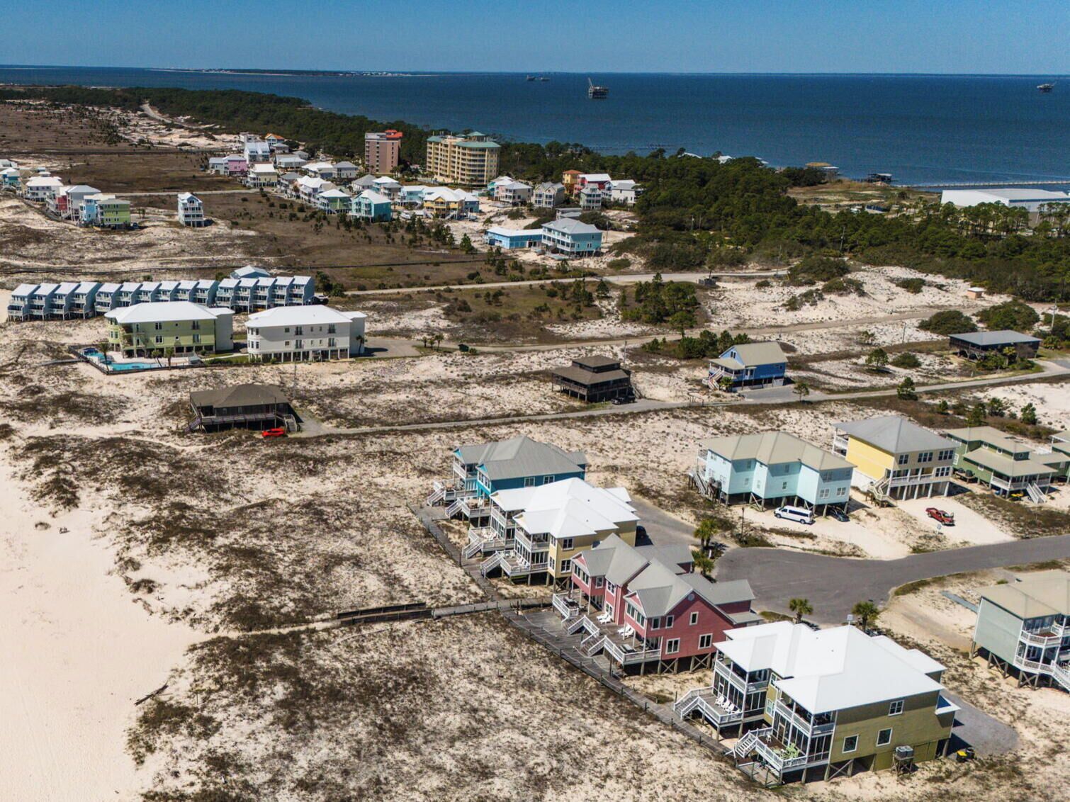 Zona costera con propiedades frente al mar, incluyendo edificios de varios pisos con balcones, algunos con acceso directo a la playa.