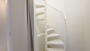 Eine weiße Wendeltreppe mit Handlauf und einer Tür zu einem Raum.