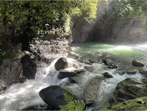 A rocky stream with water flowing over rocks, surrounded by greenery. - Casa Morpho, Modern Studio with Unique Waterfall Views (La Amistad)