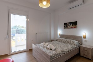 Ein Schlafzimmer mit einem Bett, einem Nachttisch, einer Wandleuchte, einer Heizung und einer Glastür zu einem Balkon.