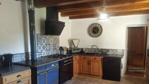 A kitchen with a stove, oven, and cabinets, a sink, and a wall clock. - Mas du Roy (Sénéchas)