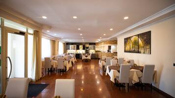 A spacious dining area with multiple tables and chairs, a bar area with a stone accent wall, and a large abstract painting on the wall.
