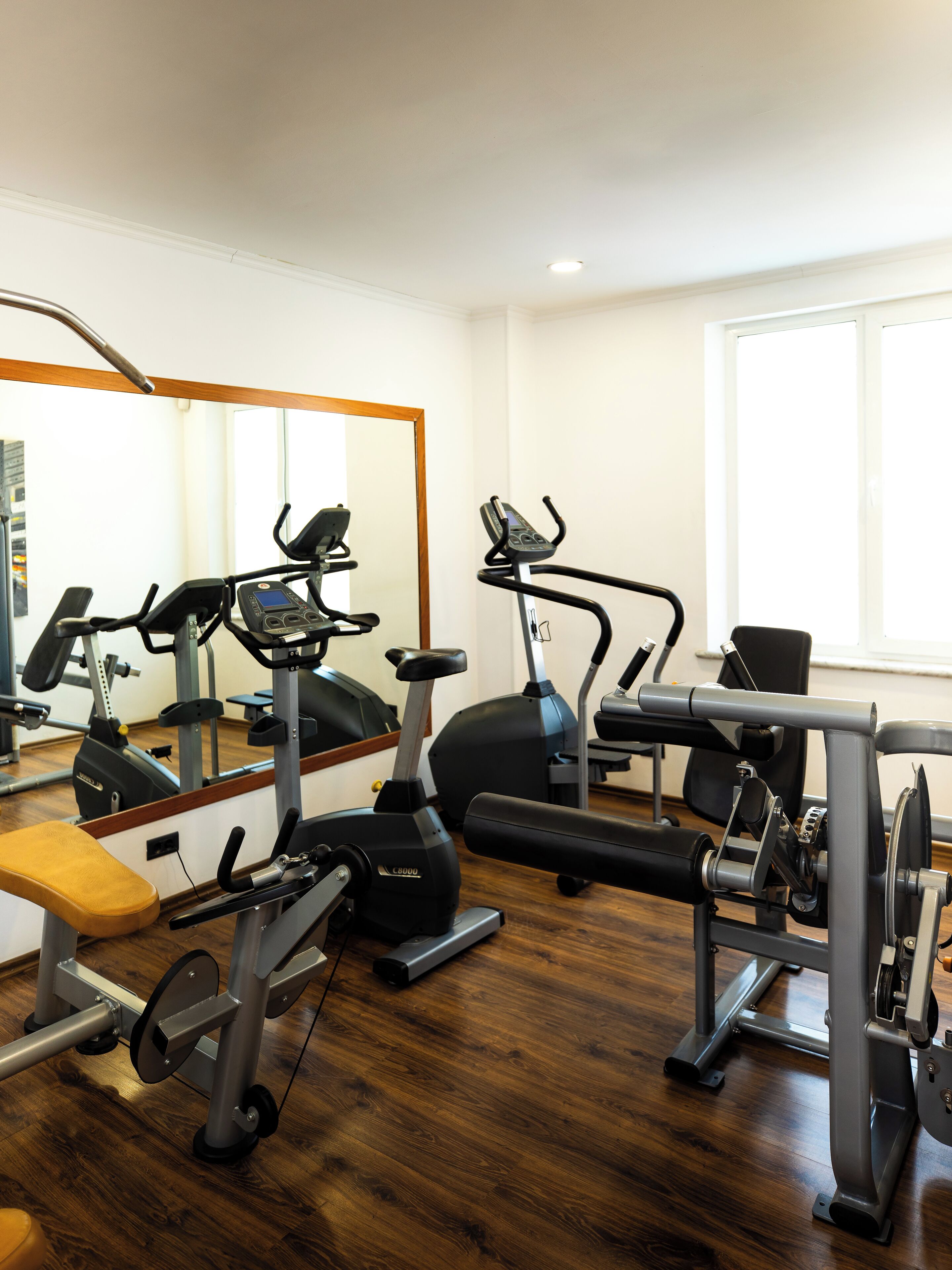 A gym with exercise equipment, a bench, and a mirror.