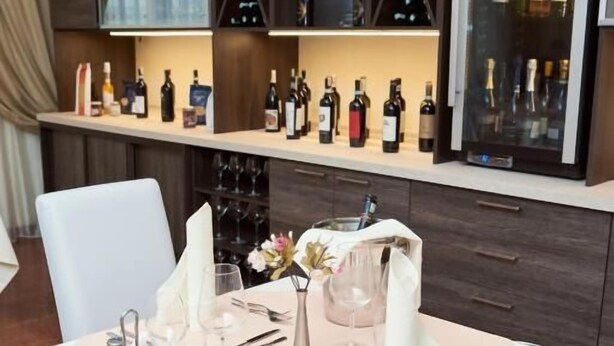 A table set for dining with a wine rack in the background. - Pushkin Hotel (Uralsk)