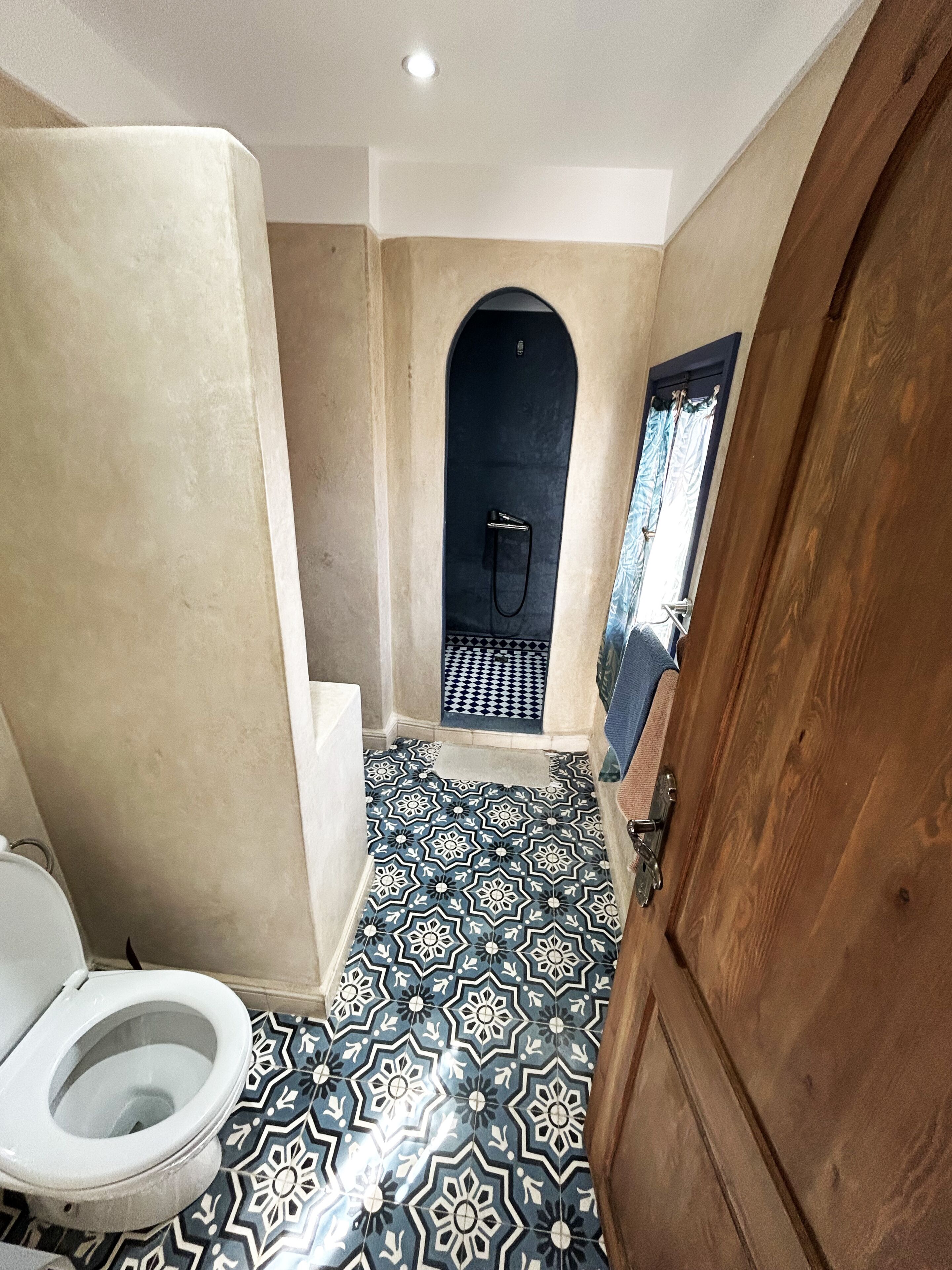 Une salle de bain avec un carrelage décoratif, des toilettes et un espace douche.