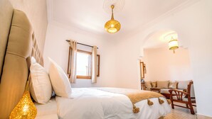 A bedroom with a bed, a lamp, a chair, and a window. - Riad Dar Ganne (Essaouira)