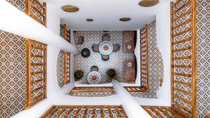 A room with a patterned floor, a central table with chairs, and a decorative wall. - Riad Dar Ganne (Essaouira)