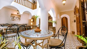 A spacious courtyard with a round table, chairs, and a staircase. - Riad Dar Ganne (Essaouira)