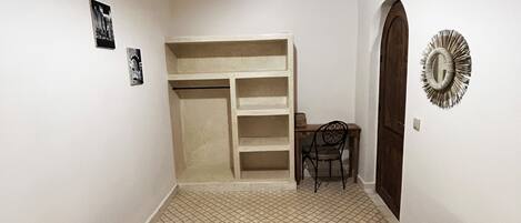 A room with two beds, a desk, a chair, a wardrobe, and a decorative mirror.