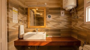 Un baño con tocador de madera, un lavabo, un espejo y un perchero para toallas.
