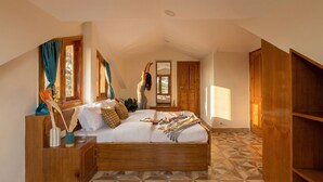 Un dormitorio con una cama de madera, una mesita de noche, un espejo, una ventana con cortinas y una puerta.
