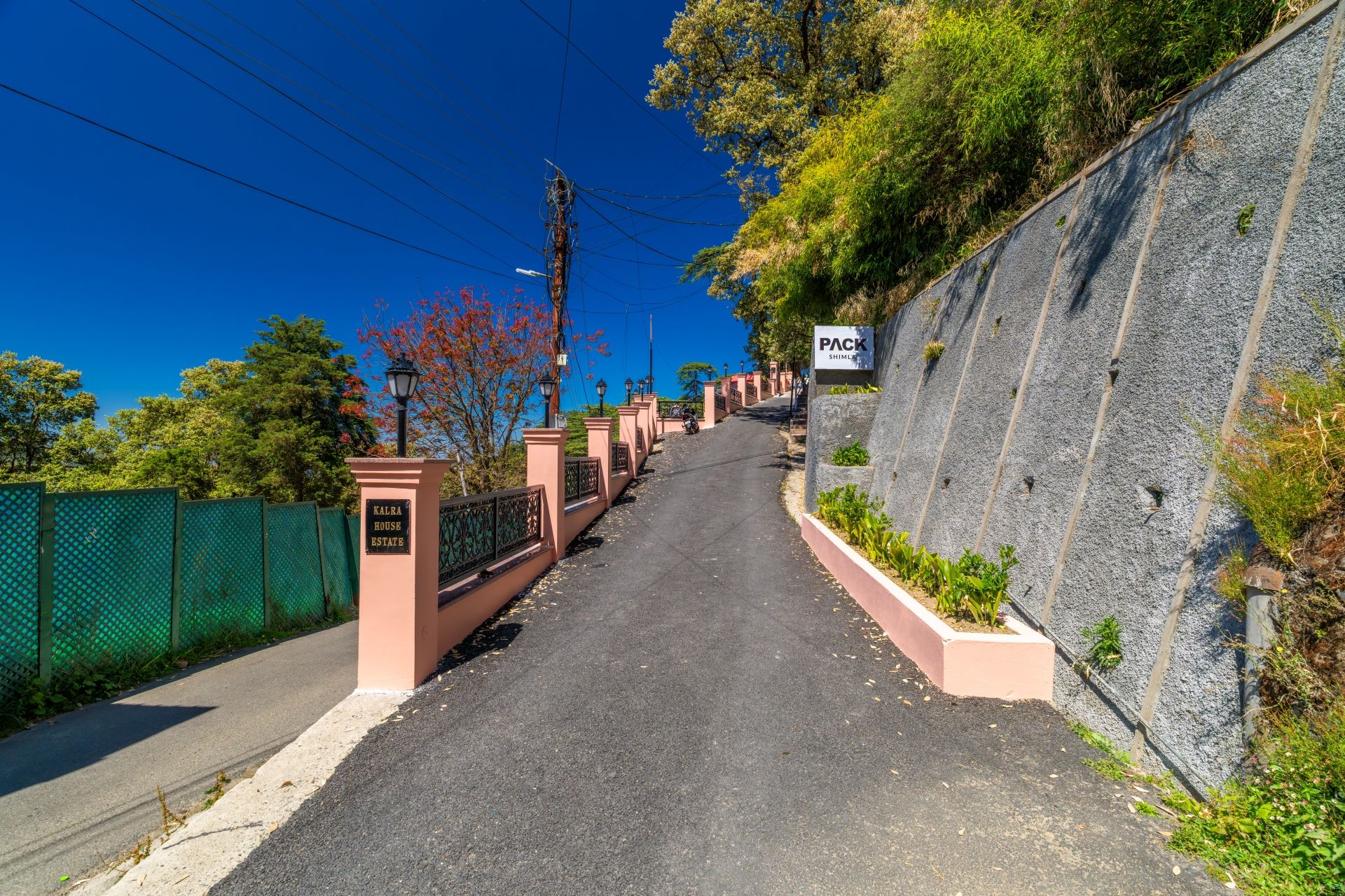 A pathway leading to a gated area with a sign reading 'PACK SHIMLA' and 'KALRA HOUSE ESTATE'.